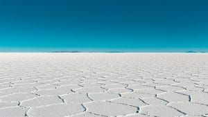 Vast salar with geometric patterns under a clear blue sky in Bolivia's Uyuni.