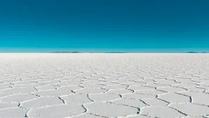 Vast salar with geometric patterns under a clear blue sky in Bolivia's Uyuni.