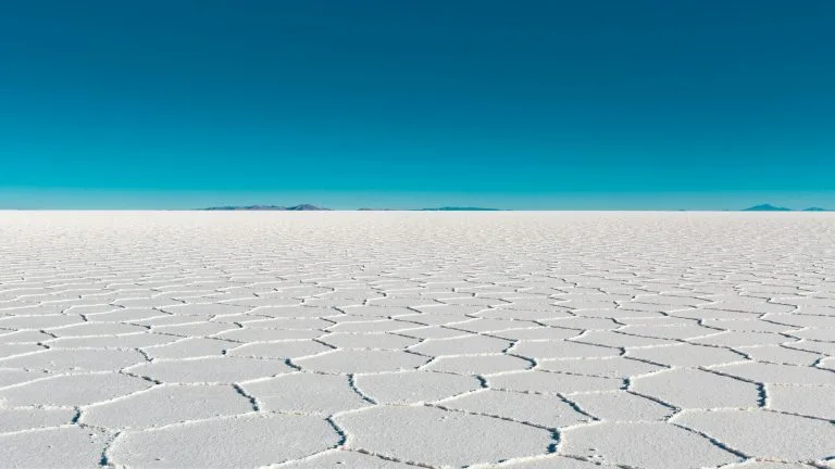 Vast salar with geometric patterns under a clear blue sky in Bolivia's Uyuni.